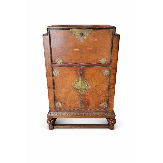 Offered here is an exceptional rare Prohibition-era liquor cabinet featuring leather-wrapped panels, brass nail head trim,...