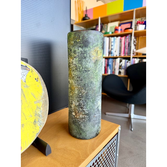 This cylindrical art glass vase features a heavily textured scavo finish achieved through the application of mineral salts...