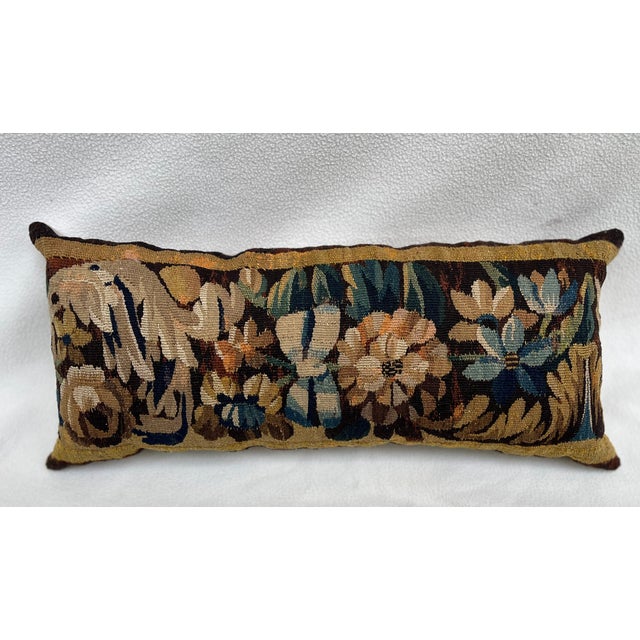 Pillow upholstered in an exquisite 18th-century tapestry featuring a charming floral motif against a rich brown ground....