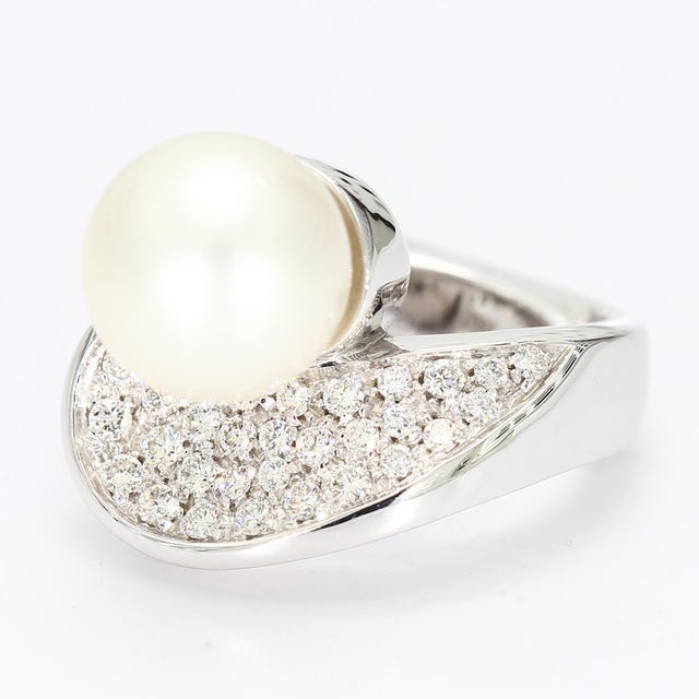 This is a luxurious bypass cocktail ring with a large white pearl at the center and a sea of thirty diamonds beneath...