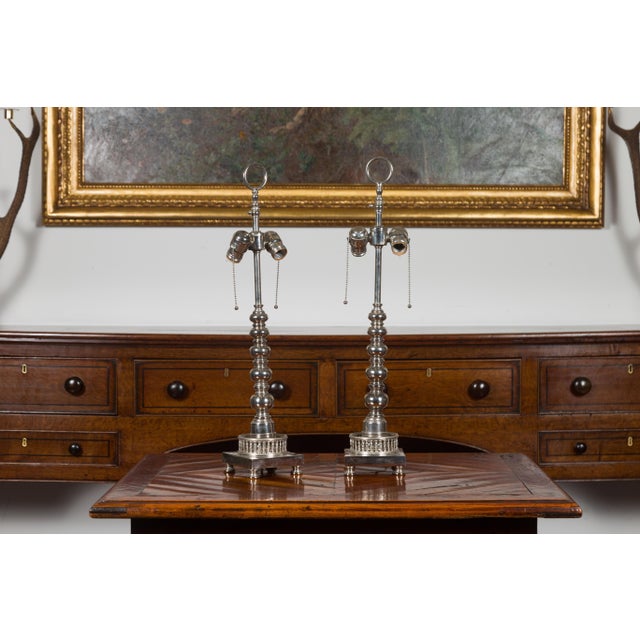 A pair of English vintage silverplate two-light table lamps from the mid-20th century, with bobbin accents and pierced...