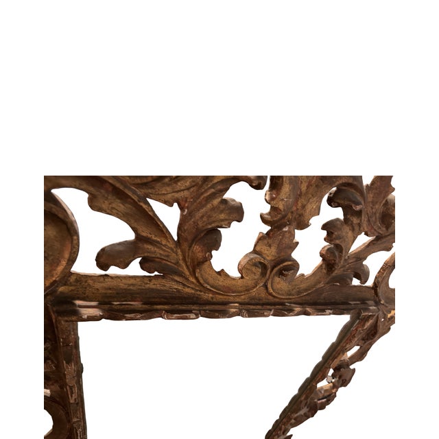 A striking and highly decorative carved giltwood wall mirror featuring elaborate openwork scrolls, acanthus leaves, and...