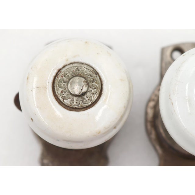 Antique door knob set with a white porcelain door knob and a nickel plated brass keyhole back plate. The backing of the...