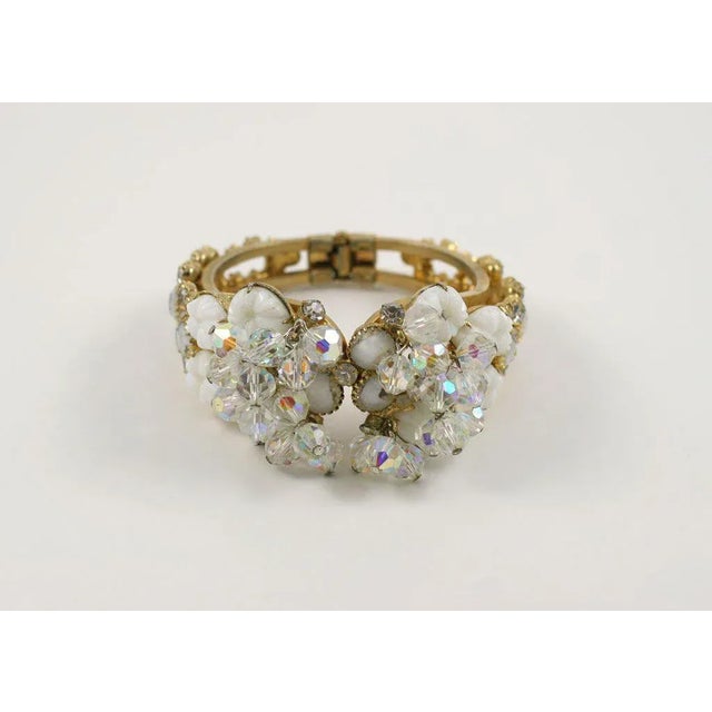 This is part of Chairish’s Costume Jewelry assortment. Crystal, rhinestone, and white beads and stones on a goldtone clamp...