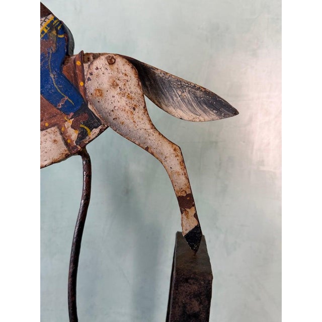 A charming vintage folk art sculpture depicting a cowboy riding a galloping horse, captured in a dynamic balancing...