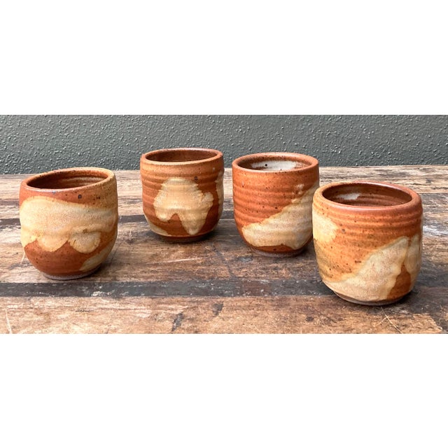 Celebrate the earthy, tactile allure of this set of four original studio pottery cups, a quintessential example of the...