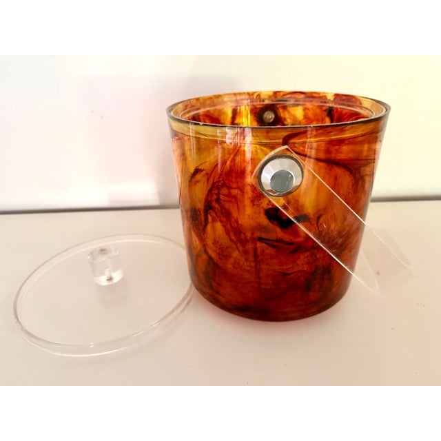 Vintage tortoiseshell Lucite ice bucket with a clear Lucite lid and swing handle attributed to George Briard. Its warm...