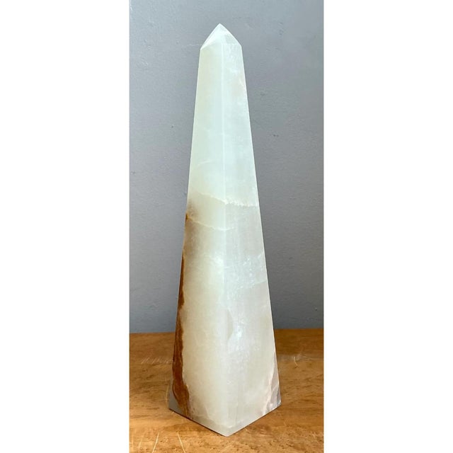 Carved from a single block of natural stone, this exquisite vintage onyx obelisk showcases a striking interplay between...