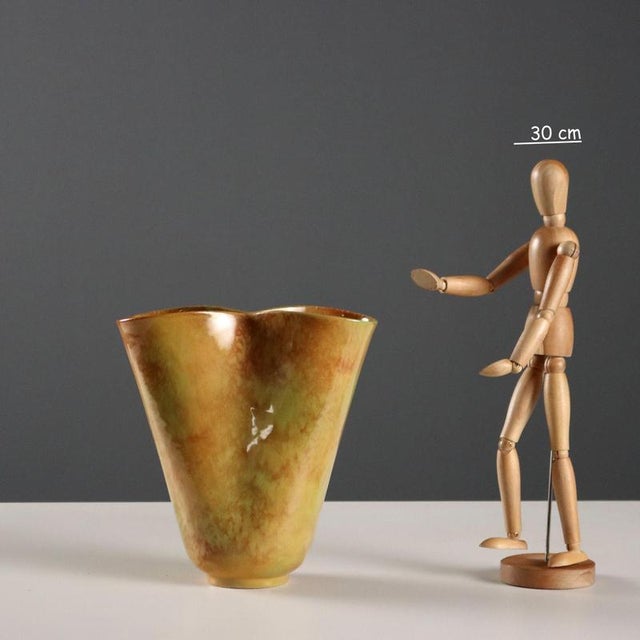 Wavy-shaped ceramic vase in shades of green and ochre. Manufacturer's mark under the base. This piece is attributed to the...