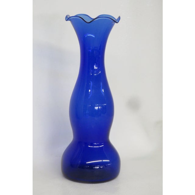 This brilliant cobalt blue Vase is made of glass. This compact vase presents a lovely vintage style with a ruffled opening...