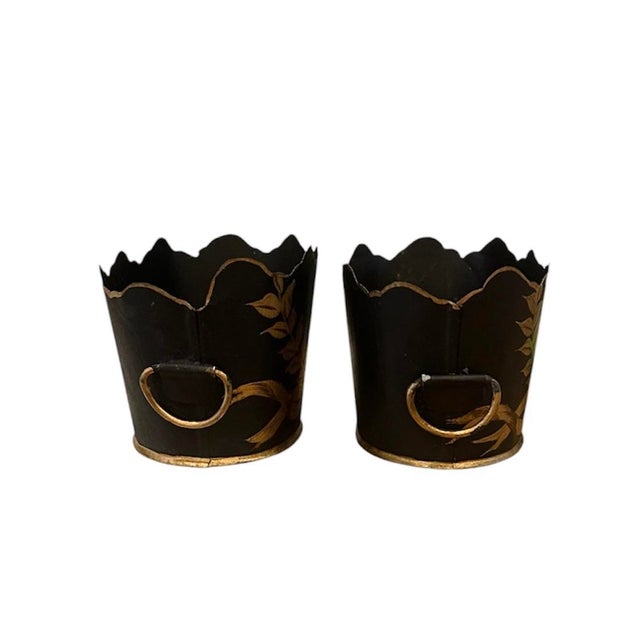 A charming pair of vintage tole cachepot planters. Each features a Monteith style, notched rim, highlighted with an...