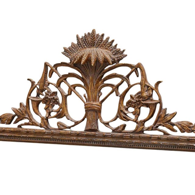 A giltwood rectangular mirror with a wheat and foliate motif crest. The beveled mirror sits in a beautifully carved...