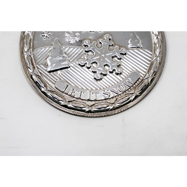 Offering a Wallace sterling silver ornament. The front depicts a landscape scene with snow falling and let it snow...