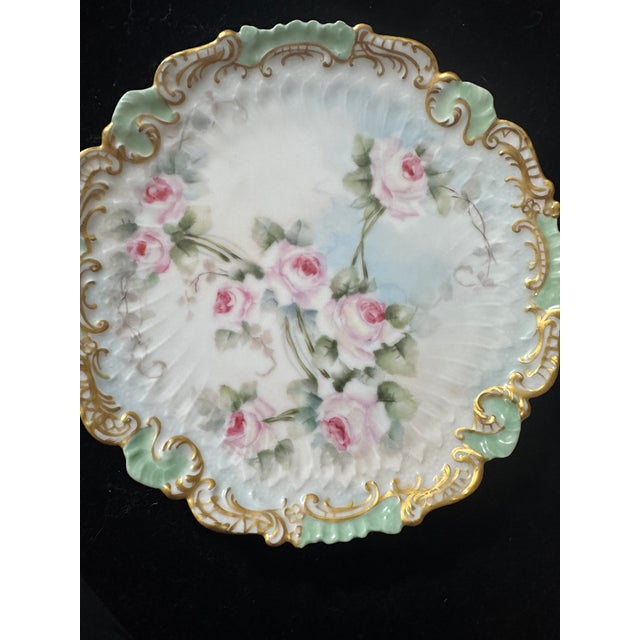 A stunning antique French porcelain cabinet or serving plate featuring a molded, scalloped rim heavily accented in heavy...