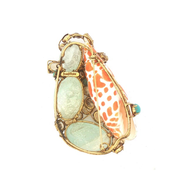 A brooch by Iradj Moini. Features aquamarine cabochons in blue and citrine ovals in orange. Accented with turquoise...