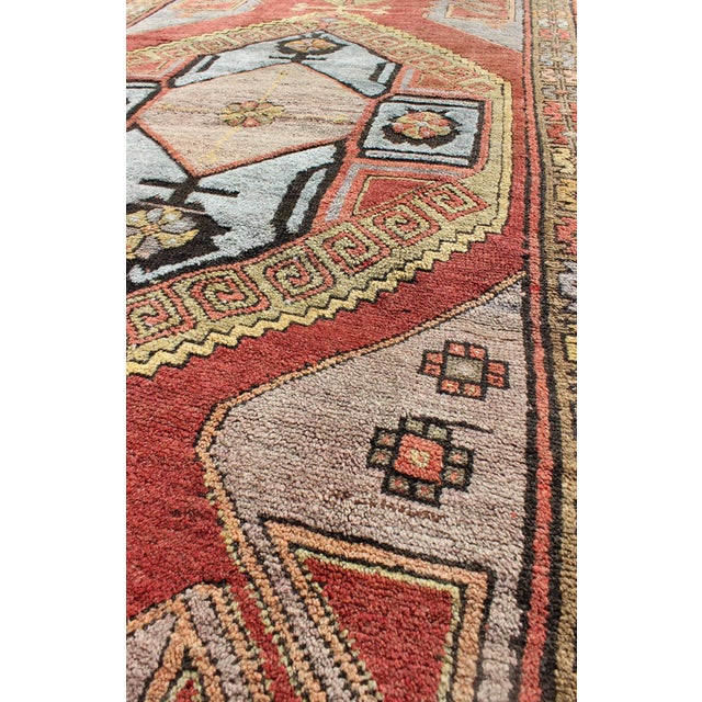 The various shades of red pair elegantly with the bold tones of light blue, yellow and charcoal, laid out over two large...