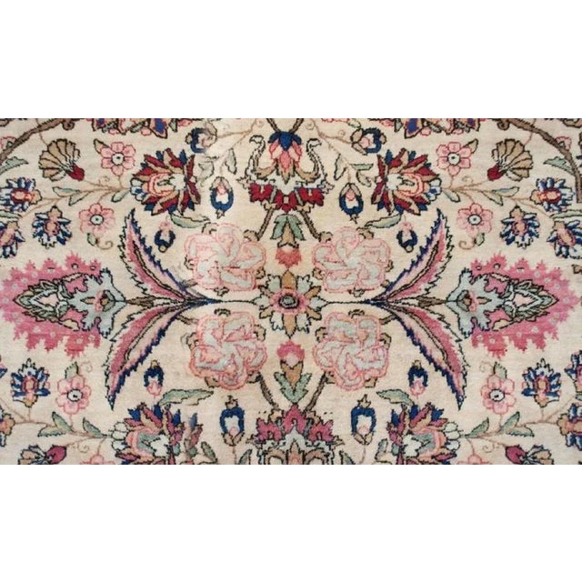 An early 20th Century Persian Kirman rug with an intensely woven multi-colored mirrored pattern of scrolling vines and...