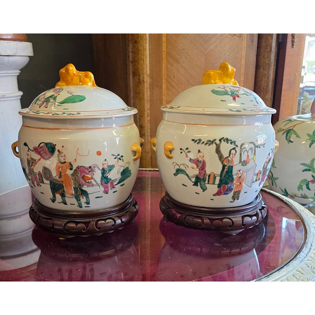 A pair of Chinese Chinoiserie handprinted rice pots from the early 1900's. They sit of heavily carved wood bases....
