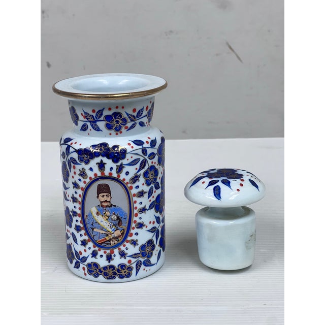 Design Plus Gallery presents an Antique 1920's Persian Vessel + Lid. A portrait of Naser al-Din Shah Qajar is included on...