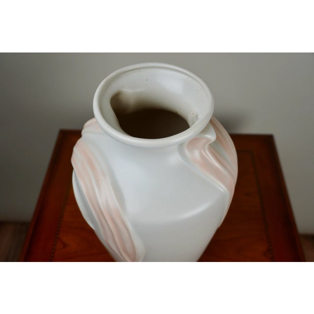 This vintage Harris Pottery vase is crafted in an elegant urn form with a soft matte ivory glaze and flowing foliate...