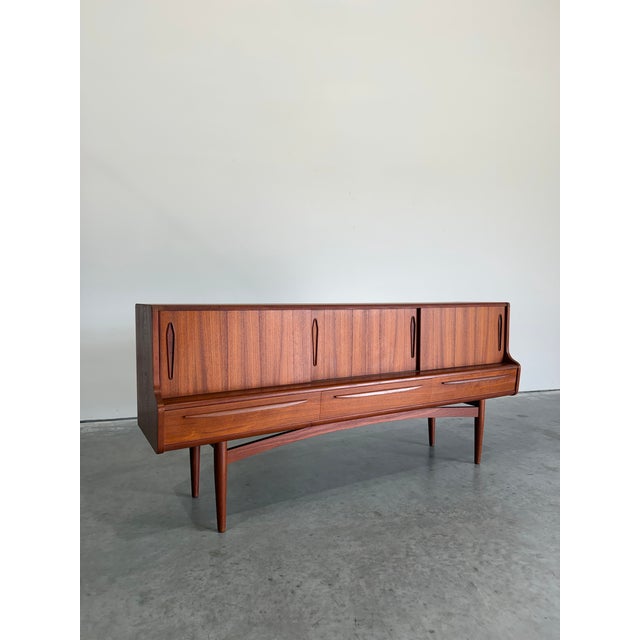 Mid Century Danish Modern Teak credenza or sideboard. Interesting step front design with recessed top featuring 3 sliding...