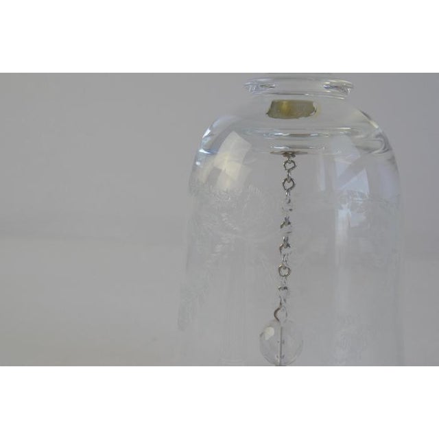 A delicate and elegant hand-etched crystal bell, featuring intricate floral patterns and a gracefully elongated handle....