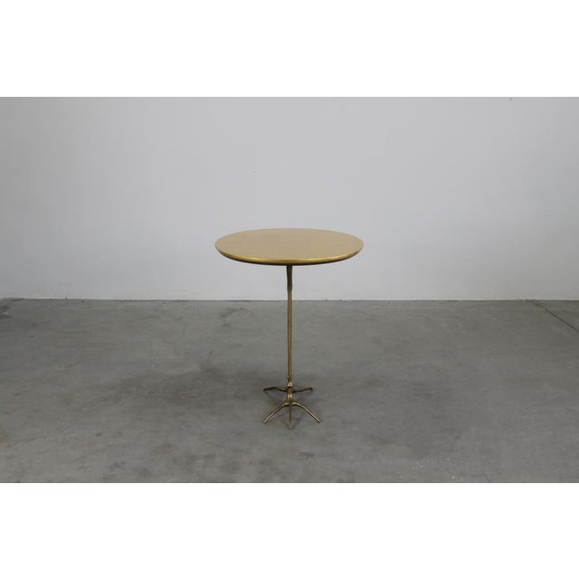Traccia side table with structure in polished cast bronze, elliptical top in plywood finished with fine yellow gold leaf....
