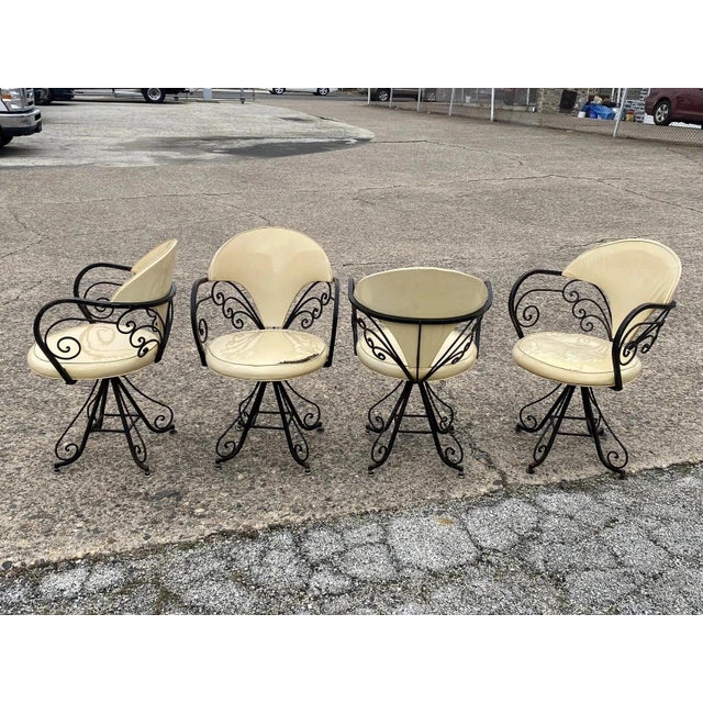 Vintage Hollywood Regency Wrought Iron Butterfly Swivel Dining Chairs - Set of 4. Chairs feature wrought iron frames,...