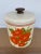 Authentic original Ransburg heavy gauge tin canister. Striking Burnt Orange flowers on a creamy custard colored...