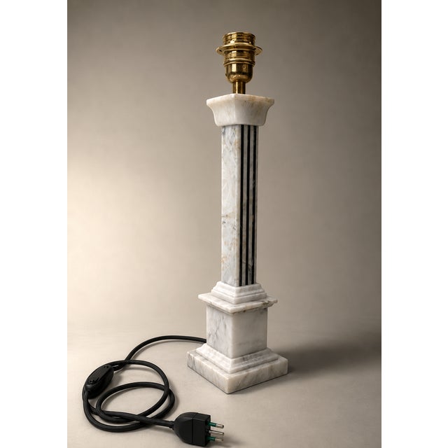 The alabaster lamp features a slender and elegant shape, with a tapered base reminiscent of a column. The body is made of...