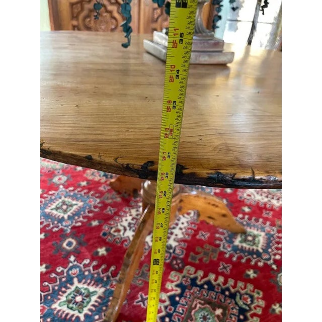 Vintage round wood pedestal table featuring a warm medium-brown finish, circular top with visible wood grain, turned...
