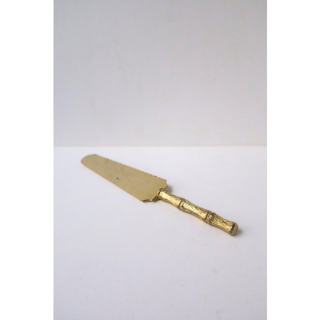 A gold-tone serving piece with bamboo-esque handle, circa 1960s. Piece is stainless steel (as marked) covered in gold gilt...
