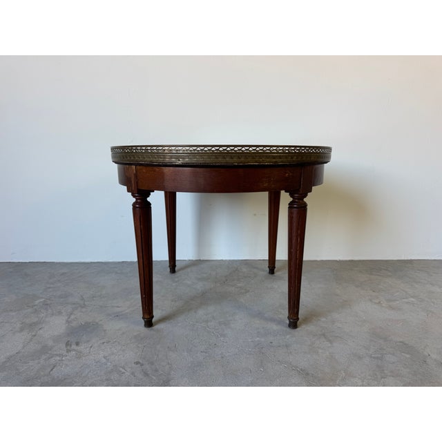 Elegant vintage Louis XVI style round coffee or side table featuring a beautiful travertine marble top framed with an...