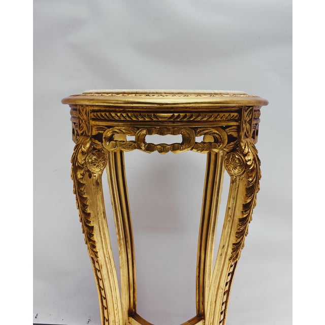 Elegant gold side table with a round marble top and richly decorated base. A special interior piece with a classic French...