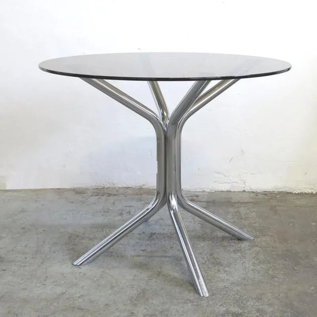 This vintage table was designed and produced in Germany in the 1970s. It features chromed legs and a smoked glass top. The...