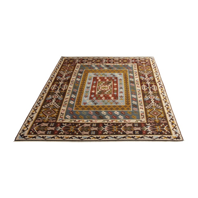 Handmade in flat-woven wool originating from Turkey circa 1920, this vintage rug is a mid-century Kilim rug of a dynamic...