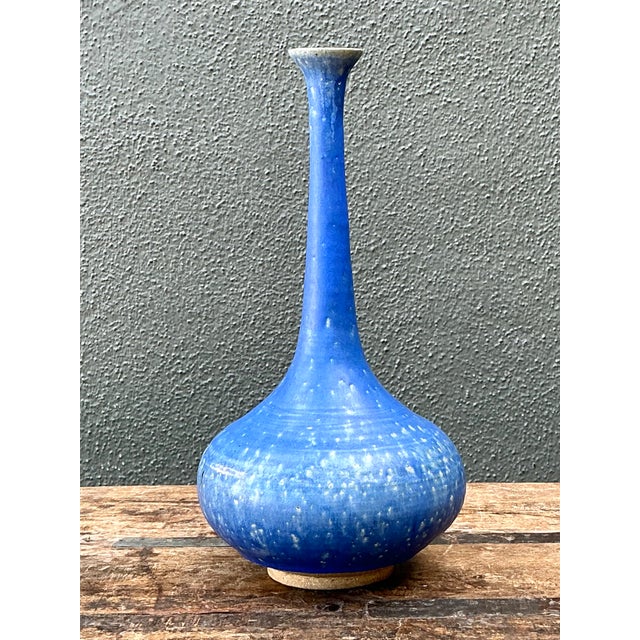 This vintage tall blue ceramic vase brings a rich cobalt hue and classic bottle form to a room. Its wide, bulbous base...