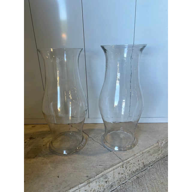 American, mid 19th century. A pair of monumental blown glass hurricane shades in colorless glass. Each with tapering form...