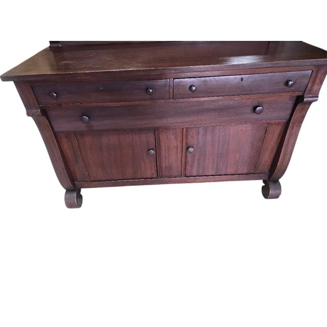 A handsome vintage solid maple Early American sideboard featuring classic Colonial styling with rolled feet, a raised...