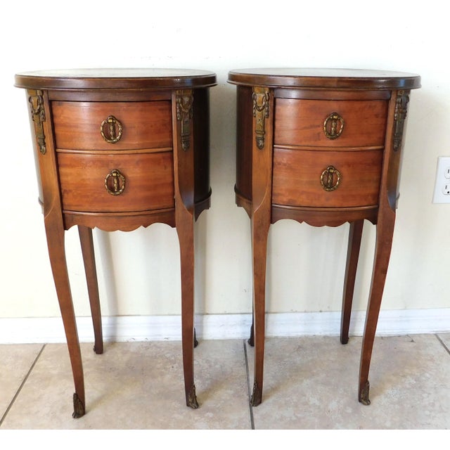 Wonderful pair of vintage French oval brass and wood side/end bedside tables. Each has two drawers. All original ornate...