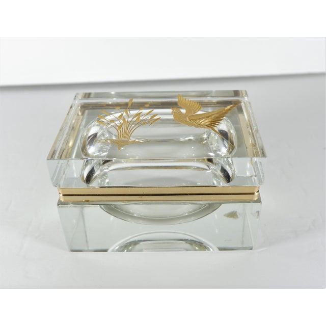 A vintage glass Murano box with hinge. Top of the box is etched with gilt gold showing a bird and plant in water. Measures...