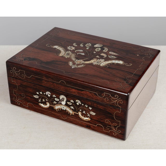 A 19th Century French Napoleon III marquetry box made of rosewood veneer with fine mother-of-pearl and brass inlay. The...