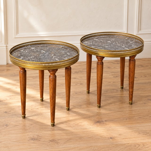 A charming matched pair of French marble-top occasional tables featuring richly patterned gray marble, pierced brass...