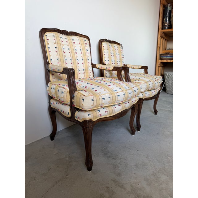 Elegant vintage Louis XV style French Provincial armchairs featuring beautifully carved walnut frames, graceful cabriole...