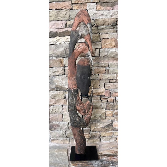 A carved wood Yipwon figure with co-centric hooks surrounding a head and painted in alternative ocher and white earth...