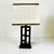 This is a lovely smaller table lamp from the 1990s. The wood lamp has contemporary Asian Chinoiserie cutouts with a linen...