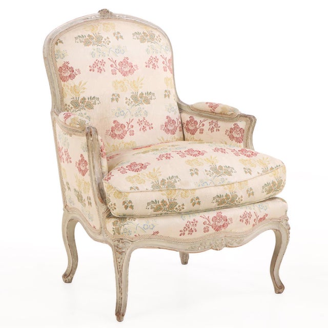 A charming pair of French Louis XV-style bergère chairs dating to circa 1940, featuring carved and painted frames with...