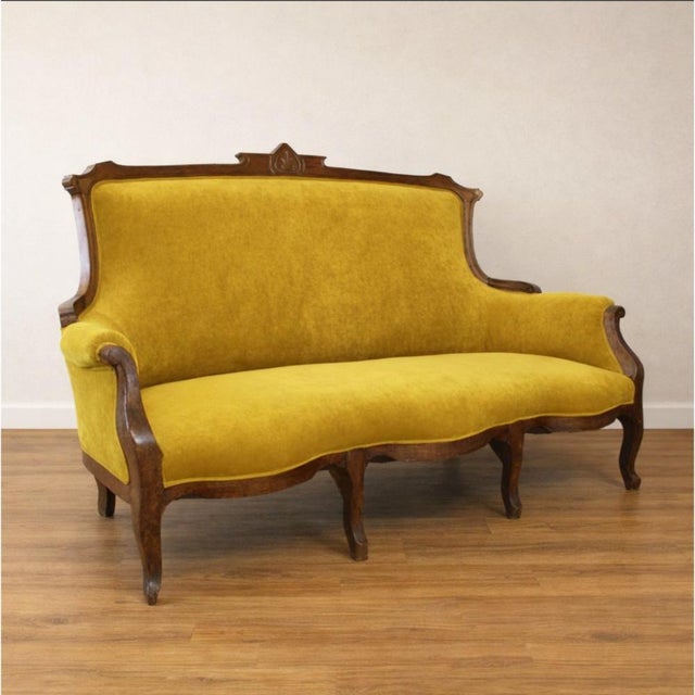 Early 20th-century Art Nouveau sofa, crafted from solid walnut and recently reupholstered in mustard-colored velvet. Its...