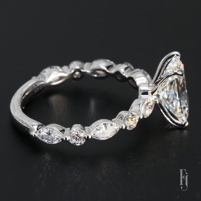 Here is a 14k White Gold Engagement Ring with One 2.02ct. Radiant E/VS1 White Lab Diamond Center as well as Six Marquise &...