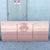 A striking postmodern waterfall dresser finished in a soft blush pink high-gloss laminate, showcasing sleek lines and...